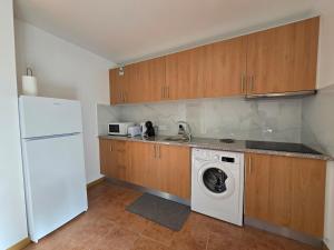 a kitchen with a washing machine and a white refrigerator at Autonomia House IV in Câmara de Lobos