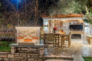 a stone patio with a table and chairs and a fireplace at Villa Aurora in Grizáta
