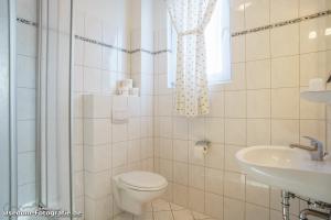 een witte badkamer met een toilet en een wastafel bij Villa Fortuna Gästehaus App Hiddensee in Ahlbeck +11 foto's