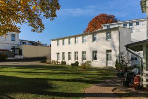 een groot wit gebouw met een grasveld bij Villa Fortuna Gästehaus App Hiddensee in Ahlbeck