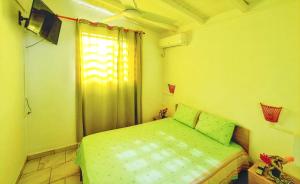 a small bedroom with a green bed and a window at Charmante Maison à Capesterre-Belle-Eau avec Jardin et Terrasse in Capesterre-Belle-Eau