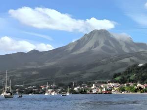 a mountain with a town and boats in the water at Maison de charme à Saint-Pierre avec vue sur mer et montagne in Saint-Pierre