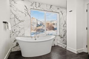 una vasca bianca in un bagno con finestra di Eden Empire with Hot Tub and Game Room Wkly Disc a Eden