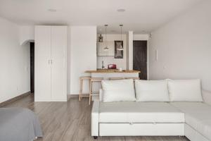 Una sala de estar blanca con un sofá blanco y una cocina. en Estúdio 21 em Santa Bárbara de Nexe - Faro, en Santa Bárbara de Nexe