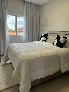 a bedroom with a large white bed with a window at Condomínio Smv in Barra Velha