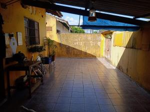 an alley with a yellow wall and a tiled floor at casa aconchegante e completa in Mongaguá