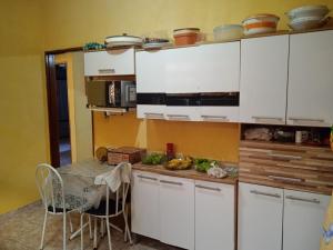 a kitchen with white cabinets and a table with food at casa aconchegante e completa in Mongaguá