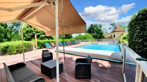 eine Terrasse mit Sonnenschirm und Swimmingpool in der Unterkunft Maison charmante au cœur de Puy-l'Évêque avec piscine partagée in Puy-lʼÉvêque