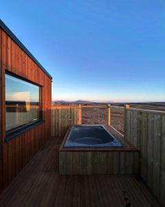 un jacuzzi en la terraza de una casa en Blue View Cabins, en Reykholt