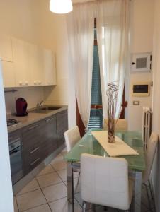 a kitchen with a glass table and white chairs at Da Serena e Lorenzo in Poggibonsi