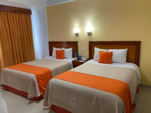 2 Betten in einem Hotelzimmer in Orange und Weiß in der Unterkunft Hotel Báez Carrizal in Villahermosa