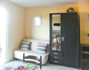 Cette chambre comprend un canapé, une chaise et une armoire. dans l'établissement Studio charmant à Hyères - 20 m² - Terrasse accueillante, à Hyères 5 autres photos