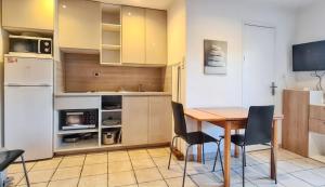 a kitchen with a table and chairs and a refrigerator at Studio charmant à Hyères, 20 m², jardin et parking privé in Hyères