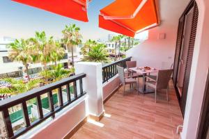 a balcony with a table and chairs and palm trees at Cozy apartment in Playa de la Américas, 60 m² with pool in Playa de las Americas