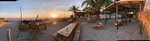 a beach with tables and benches on the beach at Viento Este Guest House in Popoyo +5 photos