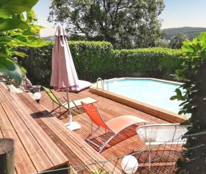eine Terrasse mit Stühlen und einem Sonnenschirm neben einem Pool in der Unterkunft Maison de caractère à Pierrefiche avec piscine privée in Pierrefiche