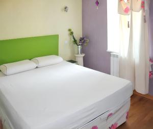 Schlafzimmer mit einem großen weißen Bett mit einem grünen Kopfteil in der Unterkunft Maison de caractère à Pierrefiche avec piscine privée in Pierrefiche