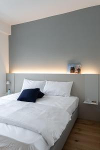 un grande letto bianco con un cuscino blu sopra di Casa Kaleido a Trento