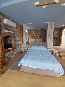 a bedroom with a large bed and a stone wall at sofitsasplace in Kokkari