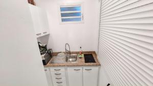 una piccola cucina con un lavandino e una finestra di Bungalow charmant à Capesterre 67 m² avec piscine partagee a Capesterre-Belle-Eau