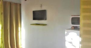 a tv on a wall next to a microwave at Bungalow charmant à Saint-François avec jardinB in Saint-François