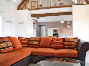 an orange couch in a living room with a kitchen at Maison charmante à Levroux avec jardin et spa in Levroux