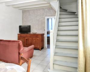 a staircase in a living room with a chair and a television at Chaleureuse Maison de Campagne avec Terrasse et Cheminée in Lignières-de-Touraine