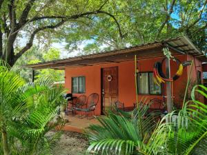 a small red house with chairs and a porch at Pinilla Highlands Incredible mountain views in Tamarindo