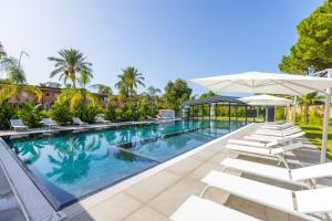 a swimming pool with white chairs and umbrellas at Gemme di Portorosa in Furnari