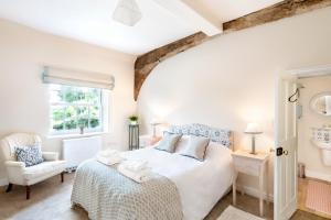 a white bedroom with a bed and a chair at Chantry Cottage - Newby Hall, Ripon, North Yorkshire in Copt Hewick