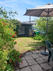 a patio with an umbrella and a bench and roses at Maison accueillante à Camaret-sur-Mer - Jardin spacieux 38 m² in Camaret-sur-Mer