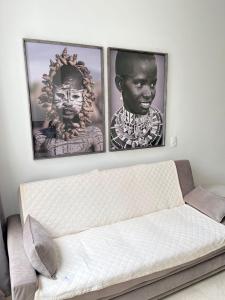 three framed pictures of three men on a wall above a couch at LK Centro 3 in Belo Horizonte