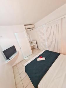 ein Schlafzimmer mit einem Bett mit einer schwarzen Decke und einem Kühlschrank in der Unterkunft Charmant appartement à La Trinité avec piscine partagée - 40 m² in La Trinité