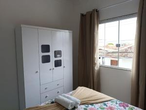 a bedroom with a bed and a dresser and a window at Casa Praia de Conceição Barra-ES in Conceição da Barra