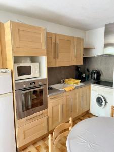 a kitchen with wooden cabinets and a white microwave at Appartement charmant à Canet-en-Roussillon / 35 m² / Piscine. in Canet-en-Roussillon