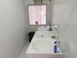 a white bathroom with a sink and a mirror at Casa Praia de Conceição Barra-ES in Conceição da Barra