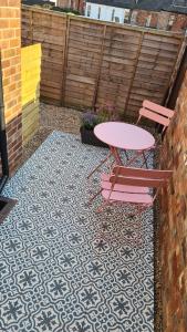 a pink table and two chairs on a patio at City Cottage in Lincoln