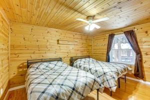 two beds in a log cabin bedroom with a ceiling fan at Less Than 1 Mi to ATV Trails Cadillac Golf Retreat! in Cadillac
