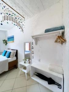 a white bedroom with a bed and a mirror at Suites Casa Azul-Vila do Abraão- conforto, limpeza, ótima localização in Abraão +50 photos