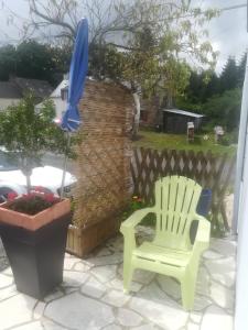 a green chair and an umbrella on a patio at Bord de vilaine in Nivillac