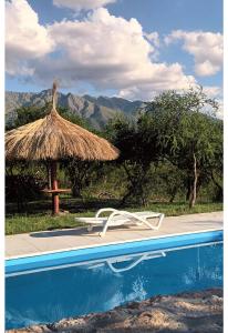 a pool with two chairs and a straw umbrella at Refugio de las Nubes in Las Rabonas