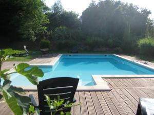 a swimming pool on a deck with a chair and a table at Auberge Les Glycines in Cancon