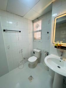 a white bathroom with a toilet and a sink at NAZ Properties in Abu Dhabi