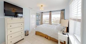 a bedroom with a bed and a dresser with a television at Cottage Four DIRECT OCEANFRONT Romantic Cottage Best Beach - Walk to Restaurants - Downtown only 5 Miles in Saint Augustine Beach
