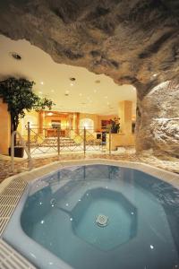 uma banheira de hidromassagem num quarto com uma parede de pedra em Sporthotel Kirchler em Tux