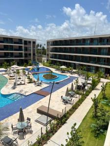 odkryty basen ze stołami i krzesłami oraz budynek w obiekcie MALIA BEACH - Alto Padrão - PRAIA MURO ALTO - Porto de Galinhas w mieście Porto de Galinhas