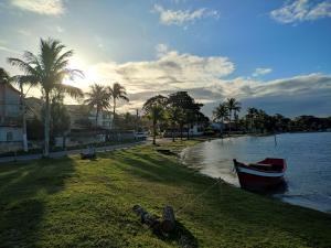 a boat sitting on the grass next to the water at Casa na Praia da Pitoria in São Pedro da Aldeia