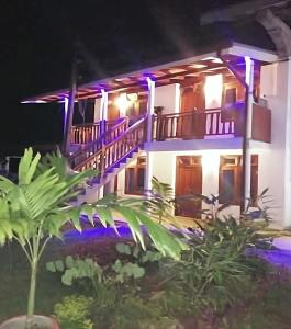 a house with purple lights on it at night at Wimal Wood Stock Surf House in Weligama