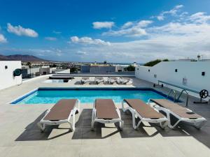 a swimming pool with chaise lounge chairs on a roof at Lovely Casa Deseada, heated pool, jacuzzi, BBQ, ping pong table in Playa Blanca