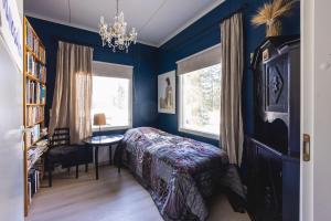a bedroom with blue walls and a bed and a table at Yövesi Atelier Home, Yöveden Ateljeekoti in Mikkeli